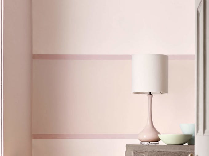 Close-up of a pale pink wall painted in 'Dorchester Pink - Pale' and a matching colored lampshade in the front.