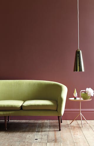 Home office with walls painted horizontally in three neutral shades and a brown baseboard, behind a wooden desk and chair.