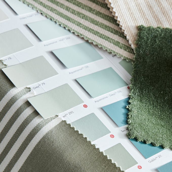 Close-up of a page from the Little Greene color card featuring greens and blues along with green and blue fabric swatches.