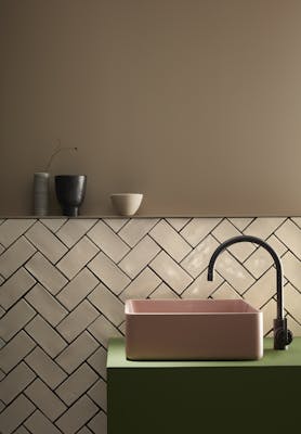 Bathroom  painted in warm neutral Rolling Fog with off white tiles underneath and a pink and green color block sink.