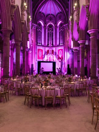 Tables, chairs and dark pink lighting at the Confetti Ball at The Monastery in Manchester, to support Breast Cancer Haven.