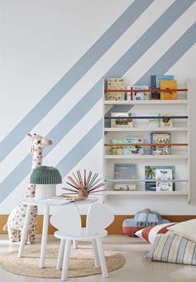 Child's reading corner painted in white (Shirting) with pale blue (Bone China Blue) diagonal stripes with a book shelf on the wall and a stuffed giraffe, table and chair.