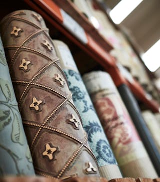 Close-up of labelled Little Greene wallpaper rolls and a surface printing roll in storage.