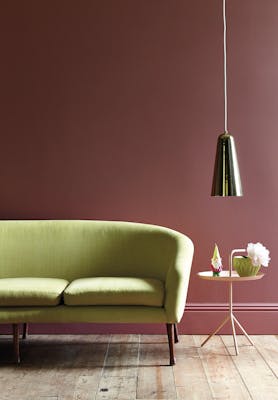 Living room painted in mid pink shade 'Ashes of Roses' with a lime green sofa on a wooden paneled floor.