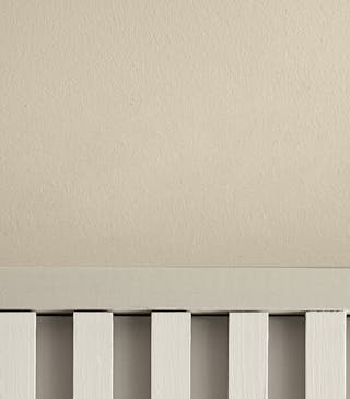 Close-up of a beige wall upper wall and cream paneling on the lower wall.