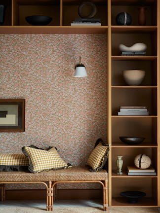 Reading nook featuring ditsy floral wallpaper (Spring Flowers - Bombolone) with shelving surround and a seat with scatter cushions.