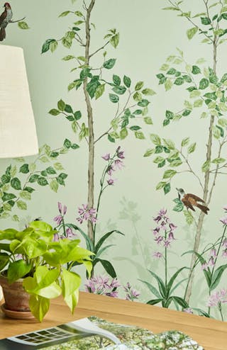 Close-up of National Trust green floral mural wallpaper featuring birds and butterflies (Bird & Bluebell - Pea Green).