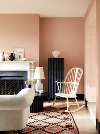 Pale pink living room in varying shades of Masquerade, alongside a rocking chair, sofa and Aztec rug.