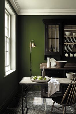 Dining area in deep green shade 'Jewel Beetle' with a wooden table and a rich brown 'Chocolate Color' dresser. 