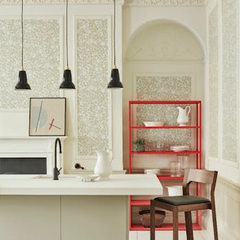 Kitchen space with framed panels of floral wallpaper in Briar Rose patter, featuring a central island and accent red shelving.