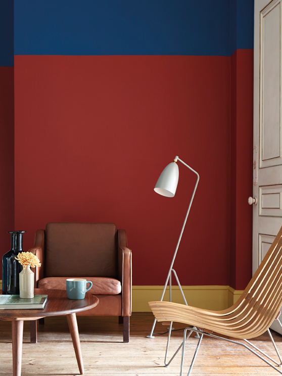 Living room painted in primary colors, red, blue and yellow with an armchair and a wooden table.