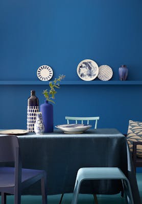 Dining room color drenched in rich blue 'Mazarine' with a dining room table and chairs.