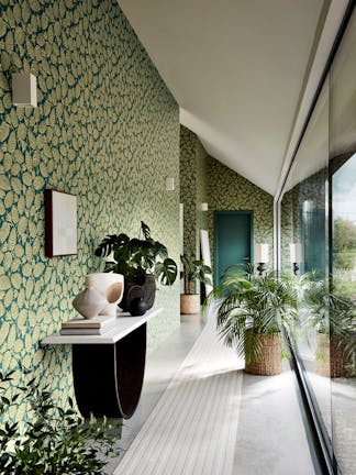 Long hallway with two tone blue and green wallpaper (Beech Nut - Florence) with a big window and plants.