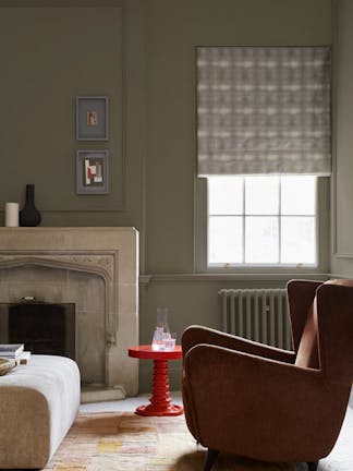 Living space with grey neutral walls (Baluster) alongside a fireplace, armchair and a bright red coffee table.