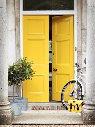 Front door painted in bright yellow 'Mister David' with two trees and a bike under pillars.