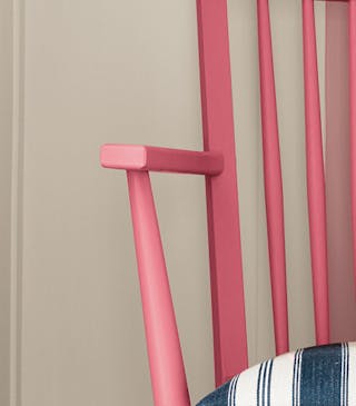 A dark pink (Carmine) wood chair featuring a dusky pink stripe painted from the wall down to a navy blue panelled floor.