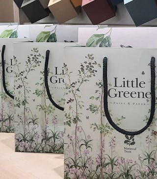 Little Greene gift bags with Bird & Bluebell print placed in a row on a table at the Little Greene Paris showroom.