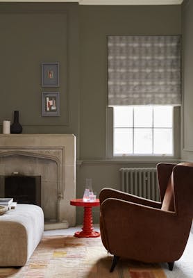 Living space with grey neutral walls (Baluster) alongside a fireplace, armchair and a bright red coffee table.