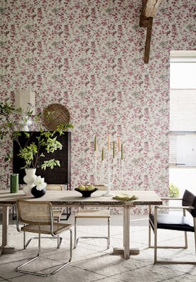 Dining room with pink printed floral and bird wallpaper (Massingberd Blossom - Mineral) and wooden dining table and chairs.