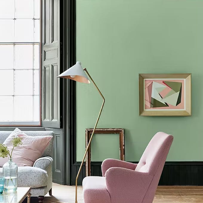 Living room painted in light green 'Pea Green' with a bright pink contrast stripe and pale pink chair.