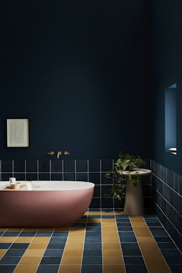 Deep blue (Royal Navy) bathroom with contrasting yellow and blue tiles and a large pink bathtub.