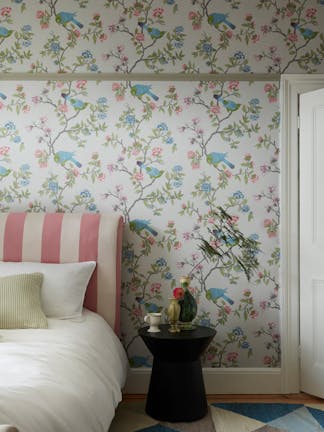 Bedroom featuring grey floral and bird wallpaper (Aderyn - French Grey) with a pink striped bed and sidetable.