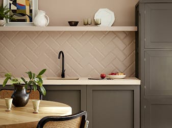 Kitchen painted in muted pink shade 'Mochi' with contrasting neutral brown 'Attic II' units with a dining room table and chair.