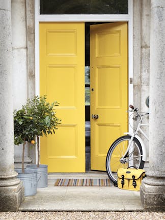 Front door painted in bright yellow 'Mister David' with two trees and a bike under pillars.