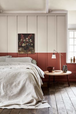 Bedroom with a light grey (French Grey) upper wall and a terracotta red 'Tuscan Red' lower wall behind a bed.