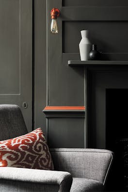 Living room color drenched in grey/ green shade 'Pompeian Ash' with a deep red contrast stripe and a grey sofa.