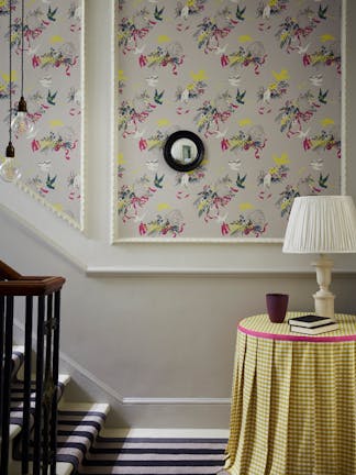 Bottom of stairs with grey bird print wallpaper (Voliéres - French Grey) and a small table with yellow gingham tablecloth.