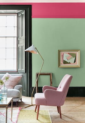 Living room painted in light green 'Pea Green' with a bright pink contrast stripe and pale pink chair.