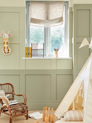 Children's nursery painted in 3 different shades of green neutral 'Green Stone' with childrens toys and a small wicker chair.