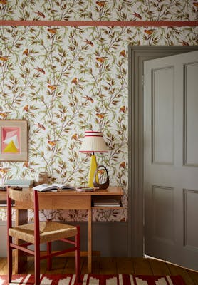 Home office space featuring bird and leaf wallpaper (Great Ormond St - Galette) with a grey door, wooden desk and chair.