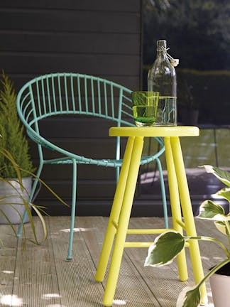 Black summer house painted in 'Lamp Black' behind two chairs painted in Green Verditer and a yellow stool in 'Trumpet'.