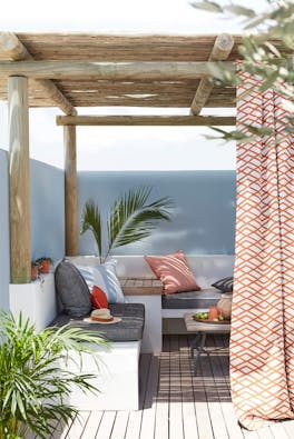 Outside lounge area with a corner seating area with the wall painted in pale blue (Bone China Blue) underneath a wooden roof.