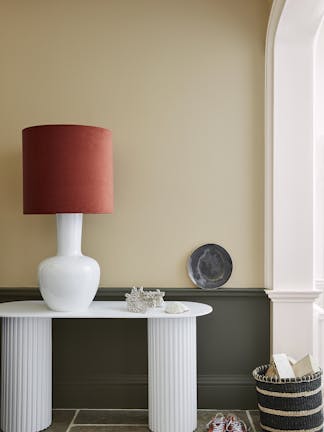 Pale brown neutral hallway (Lute) with lower wall painted in grey green (Pompeian Ash) and a white side table and large lamp.