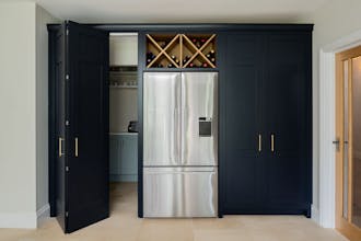 Black bi-folding cupboards on the left and right, leading into a utility room, and a silver fridge in the middle.