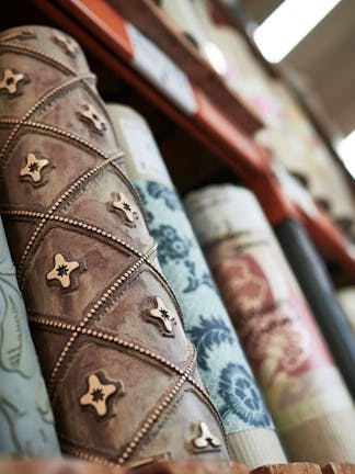 Close-up of labelled Little Greene wallpaper rolls and a surface printing roll in storage.