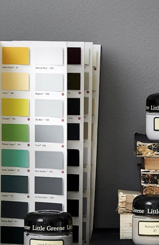 The Little Greene color card in front of a grey wall displayed alongside books, flowers and Little Greene sample pots.