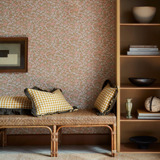 Reading nook featuring ditsy floral wallpaper (Spring Flowers - Bombolone) with shelving surround and a seat with scatter cushions.