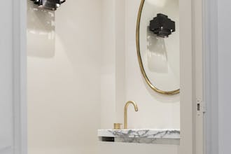 White (Portland Stone - Pale) bathroom walls with gold framed mirror and marble sink.