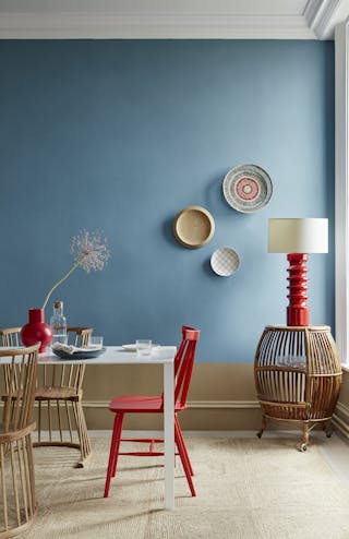 A close-up of a wall painted in Blue Verditer, a rich blue shade, adorned with circular rattan and wooden wall decorations.