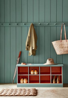 Paneled mudroom painted in green shade, Pleat, with contrasting deep red (Heat) shelving.