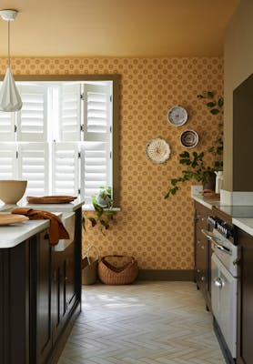 Kitchen space featuring golden yellow small print floral wallpaper (Ditsy Block - Bombolone) with a large window and dark brown cabinets.