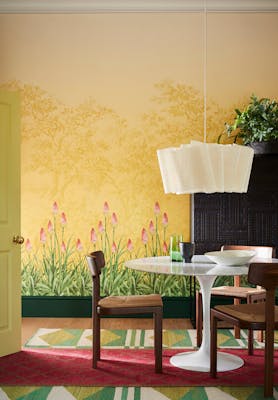 Dining room with yellow mural wallpaper (Upper Brook Street - Soleil) and a dining room table with wooden chairs.