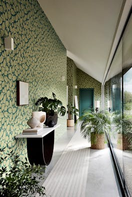 Long hallway with two tone blue and green wallpaper (Beech Nut - Florence) with a big window and plants.