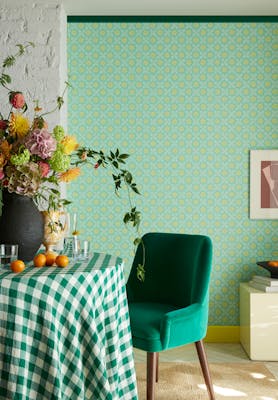 Morning room featuring vibrant green small print floral wallpaper (Ditsy Block - Green Verditer) with a table,  green chair and vase of flowers.