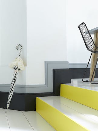 White stairs in a hallway with bright yellow (Trumpet) contrasting stair risers and a black and grey baseboard.