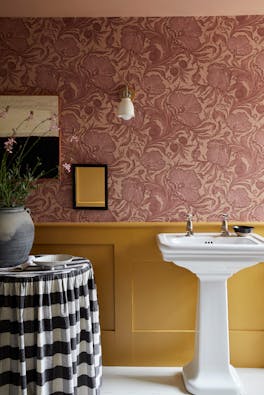 Bathroom with two-tone wall decor, featuring Poppy Trail pink floral wallpaper above and a mustard colour paint below.